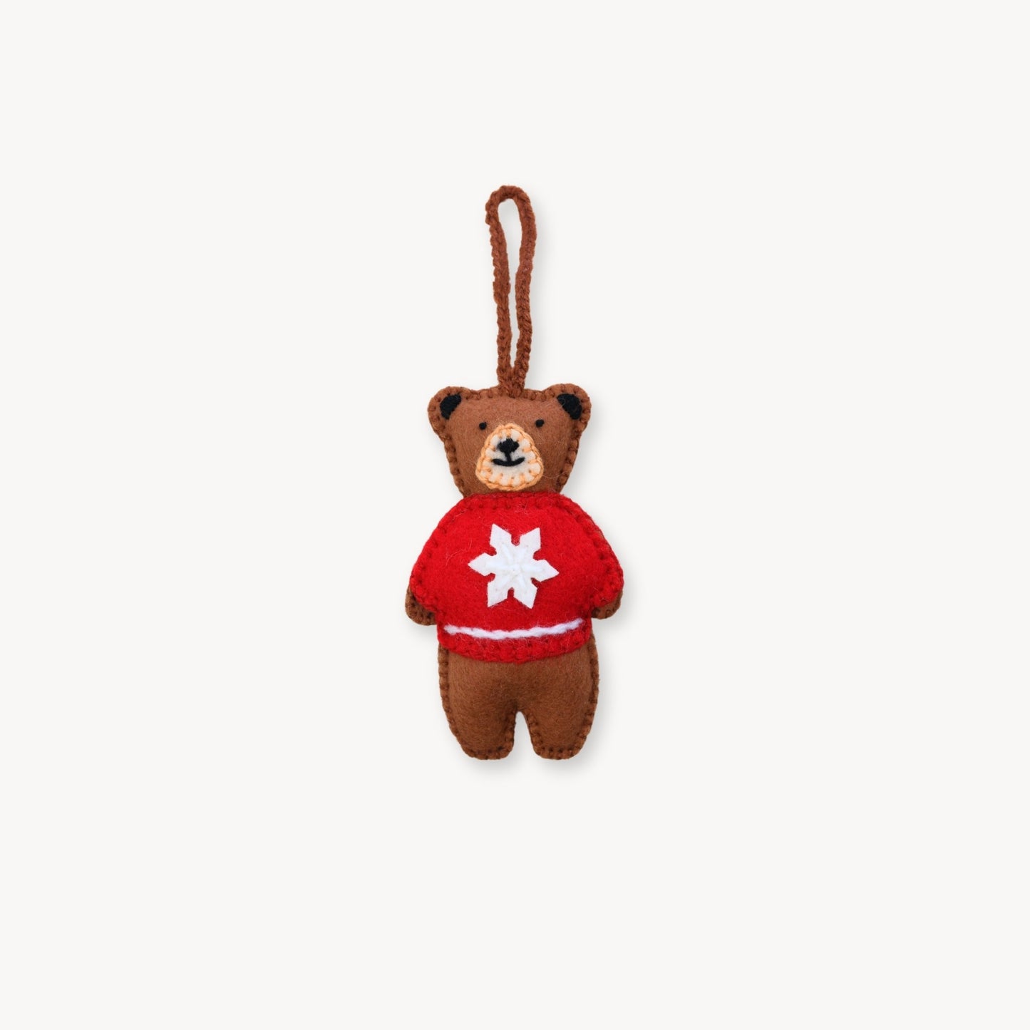 Small brown teddy bear keychain wearing a red sweater with a white star on a white background